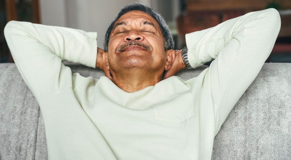 Older man leaning back relaxing with his hands behind his head | Presbyterian Village Athens