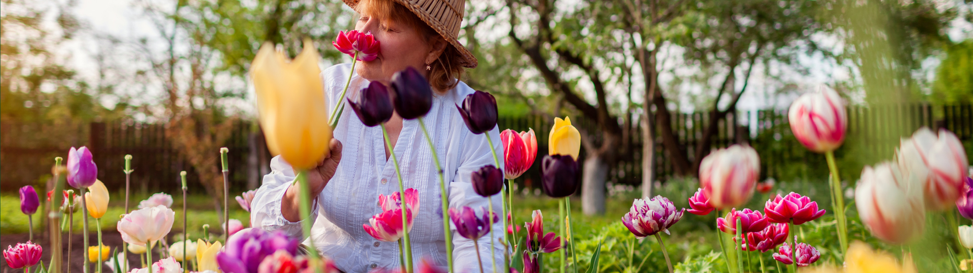 Older woman smelling flowers outside | Presbyterian Village Athens