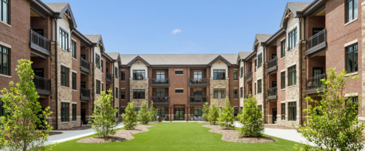 An apartment complex surrounding a beautiful, green courtyard at a senior living community in Georgia.