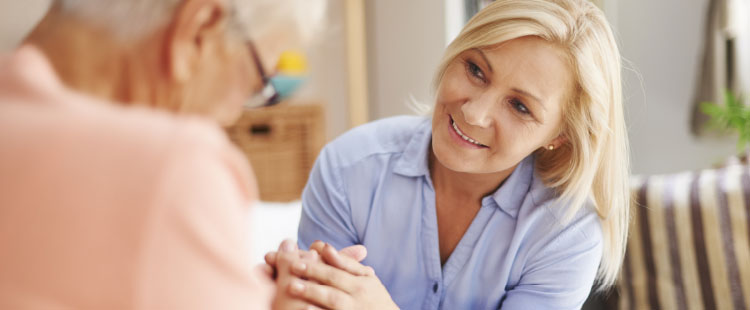 A senior woman smiles at a man in an assisted living community.