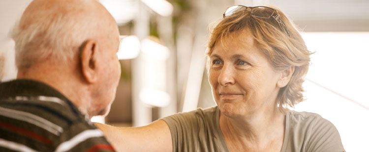 A woman smiles at a senior man.