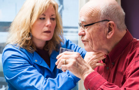 A woman helps a senior man with speech therapy.